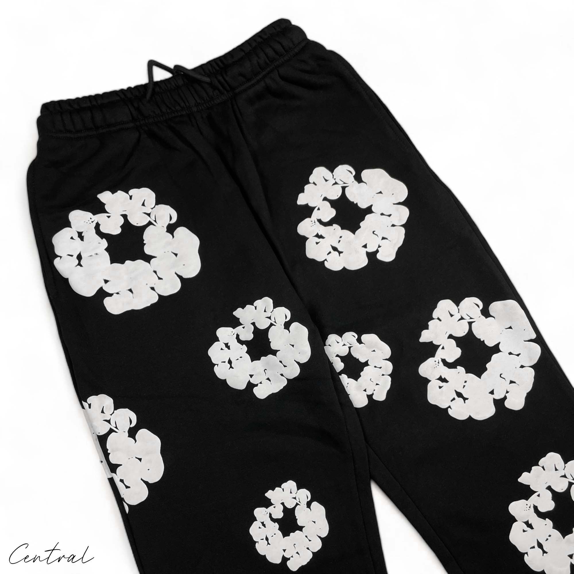 Black sweatpants by Central AE featuring a unique cotton wreath design in denim tears style.