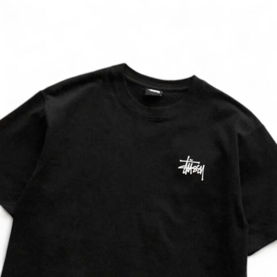 Black BASIC STÜSSY TEE featuring a classic crew neck and short sleeves, laid flat for a clear view of the fabric.