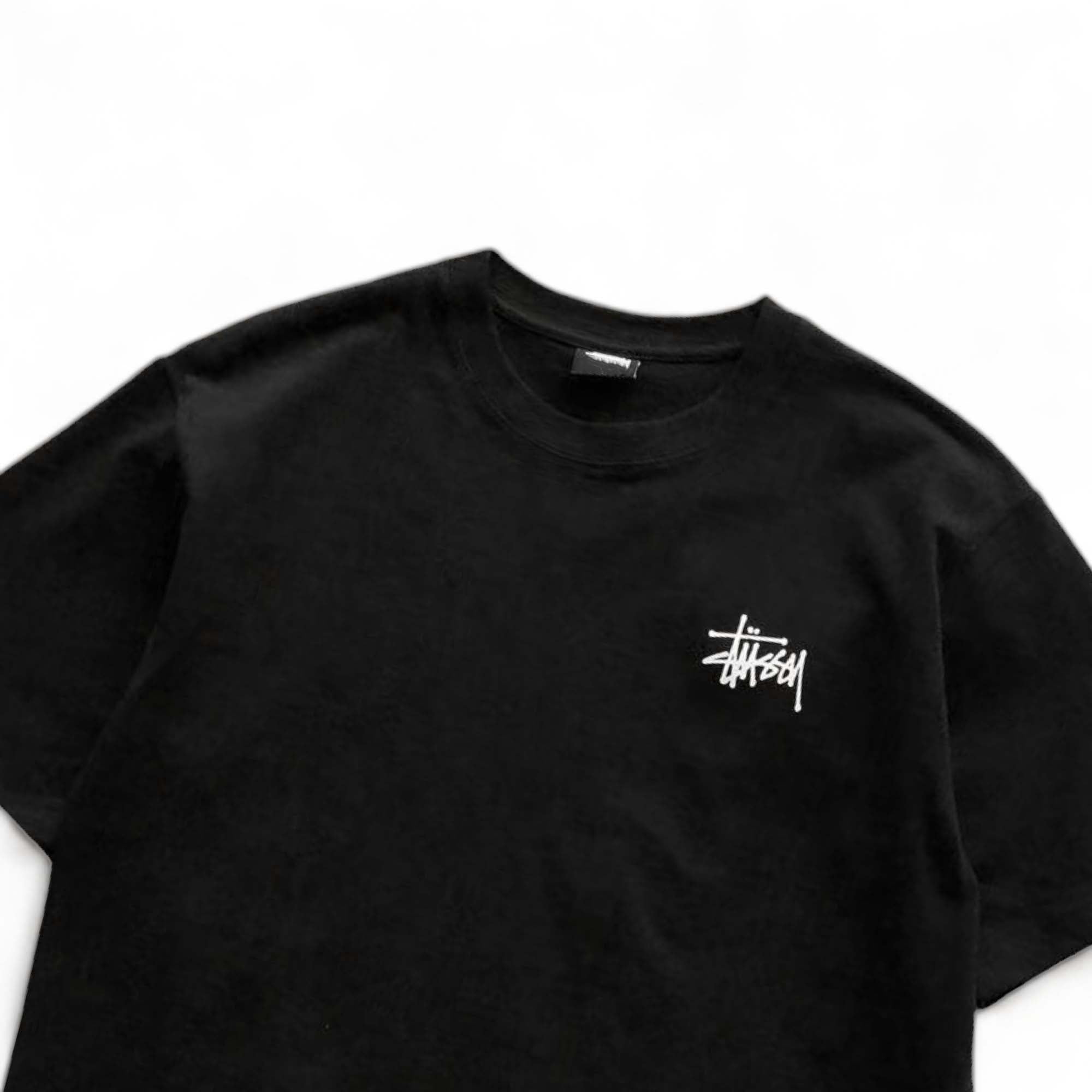 Black BASIC STÜSSY TEE featuring a classic crew neck and short sleeves, laid flat for a clear view of the fabric.